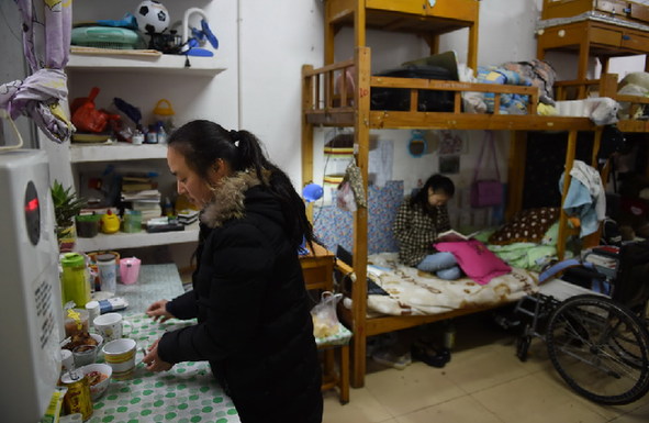 3月9日，下课后陈望坐在寝室床上看书，她的母亲在一边收拾。学校特意安排陈望和陪读的母亲单独住在宿舍楼一楼离出口最近的一间寝室。新华社记者 李尕 摄