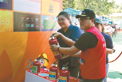 在志愿江苏嘉年华现场,参观的市民在消防志愿者小屋学习使用灭火器。梅 亮 万程鹏摄